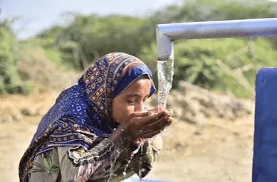 Children gathering around water containers